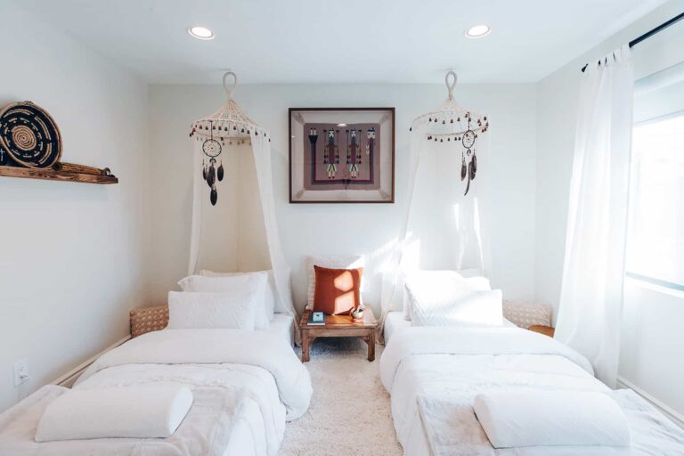 Bright bedroom with two beds, dreamcatchers, and natural light.