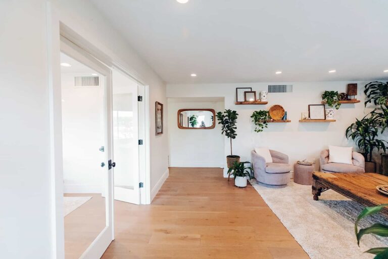 Spacious therapy area with armchairs, wooden table, and greenery.