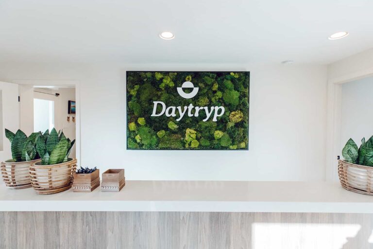 Reception area at Daytryp featuring a natural moss wall with the Daytryp logo.