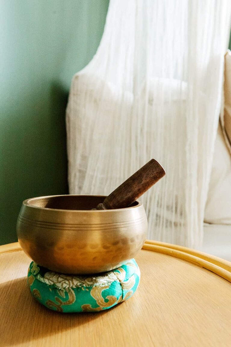 Tibetan singing bowl with wooden mallet on a cushion.