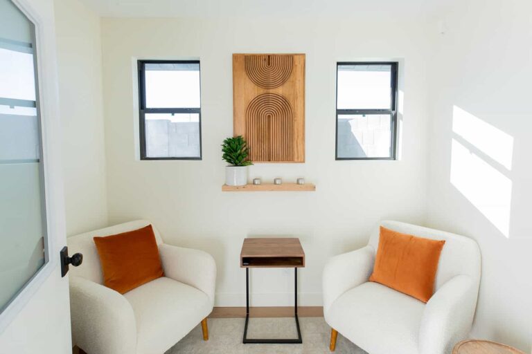 Cozy therapy room at Daytryp with two white chairs, orange pillows, and minimalist decor.
